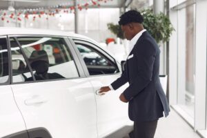 Sales adviser opening the door of a new white vehicle